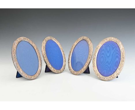 A set of four Elizabeth II silver-mounted photograph frames, each decorated with fancy birds and foliate scrolls in relief, w
