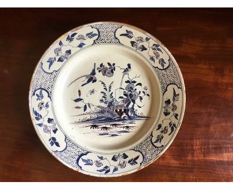 A mid 18th Century Delftware plate, probably English circa 1750, the border with geometric and floral panels, the centre with