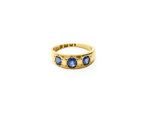 An 18 Carat Gold Sapphire Three Stone Ring, the graduated oval cut sapphires in yellow star settings, to a plain polished sha