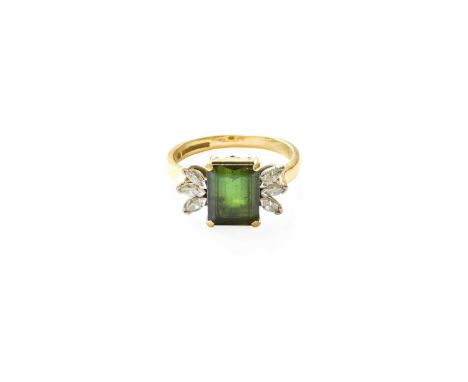 An 18 Carat Gold Green Tourmaline and Diamond Ring, the emerald-cut green tourmaline in a yellow claw setting, flanked by tri