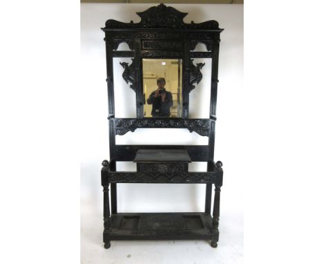 A Victorian carved oak hall stand, with beveled glass mirror to back above single drawer flanked by two umbrella wells, h. 22
