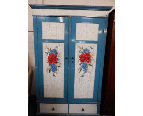 A pine wardrobe, later painted with flowers on a cream ground within blue borders, comprising two panelled doors, and two fri
