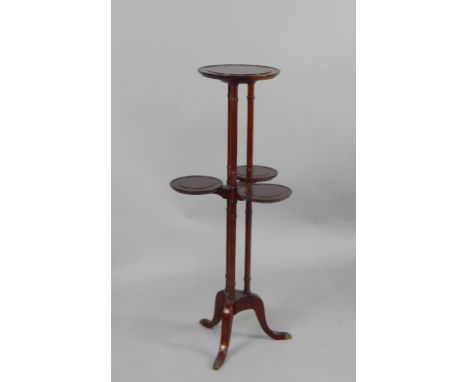 A mahogany cake stand, with three circular dished tiers, on triple turned supports, tripod base with paw feet, 109cm high