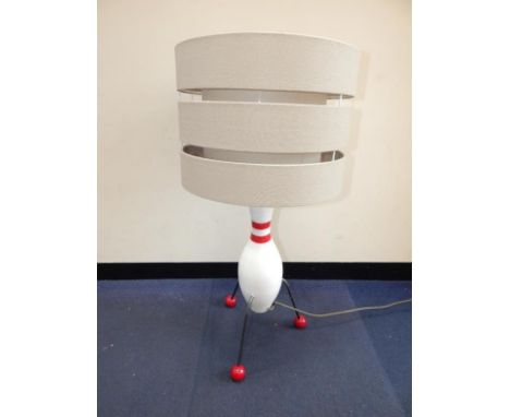 A late 20thC atomic rocket form table lamp, with a painted wooden body raised on three metal and red ball feet, with shade, 7