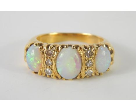 An opal three stone ring, interspersed with rows of three diamonds, set in yellow metal, size M, 6.8g.