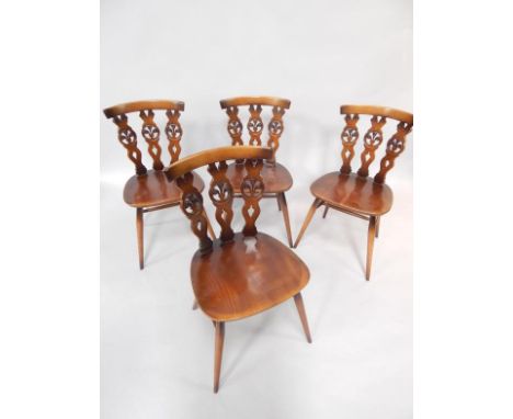 A set of four Ercol oak single dining chairs, raised on turned legs united by an H-frame stretcher.
