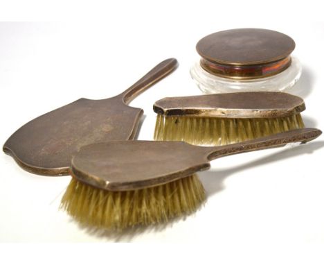 An Elizabeth II hallmarked silver dressing table set comprising two brushes, hand mirror and silver topped glass trinket pot,