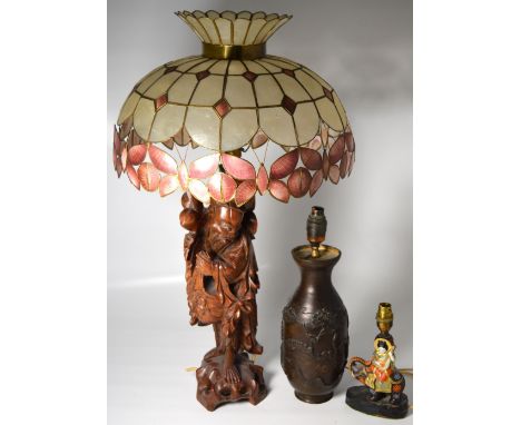 A carved Oriental style hardwood table lamp with shade, height 75cm, a spelter Oriental style table lamp decorated with peaco