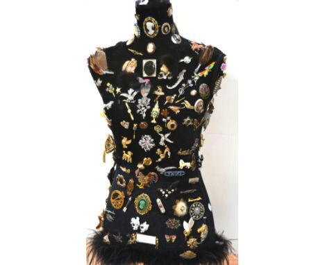 A black velvet mannequin with approx 150 brooches, various designs to include white metal flowers, birds, bugs, ceramic Pixie