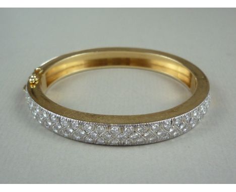 A diamond and high carat yellow metal hinged bangle, the face set with precious white metal, saltire engraved and pavé set wi