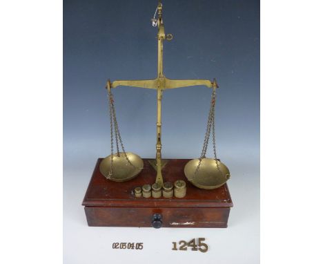 A set of Victorian counter top brass beam scales by Calipe, Dettmer and Co, on a mahogany base incorporating a drawer, togeth