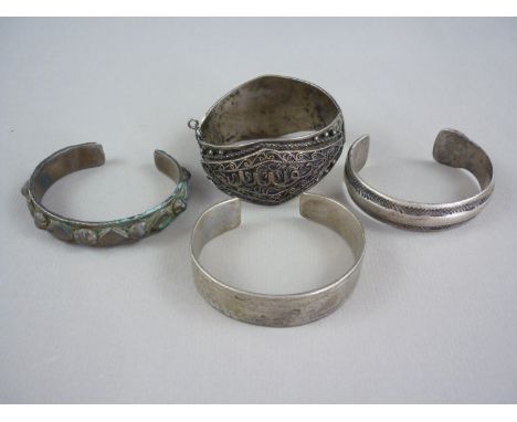 A Middle Eastern white metal torque bangle, with crudely hatched decoration and struck marks, tests as silver, together with 