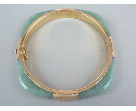 A high carat yellow metal and jade bangle, of rounded square section, mounted to each face with an engraved yellow metal coll