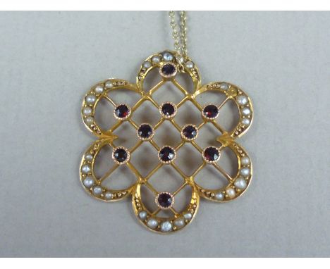 An Edwardian lady's garnet and seed pearl pendant necklace, in the form of a flower head, with central open latticework studd