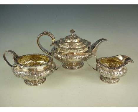 A George IV silver three-piece tea service, each element of compressed oblate form, profusely decorated with floral and folia