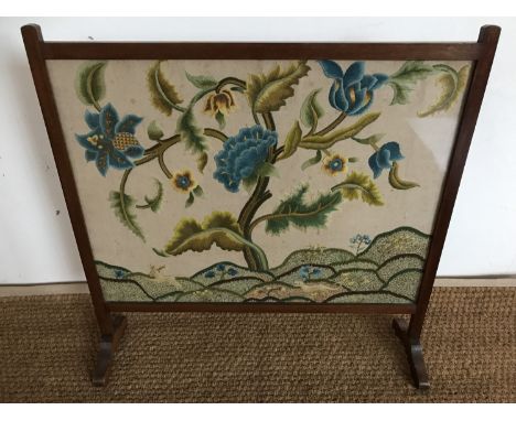 A late 1930s Jacobean crewel work embroidered fire screen, worked in blue and green wools in depiction of flowers over a line