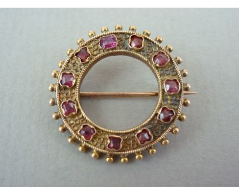 A late 19th / early 20th Century lady's almandine garnet and yellow metal brooch, of annular form, the cusped and collet set 