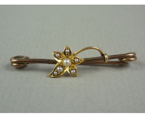 An Edwardian seed pearl set yellow metal stock pin, the bar surmounted and entwined by a pearl set flower, tests as gold 