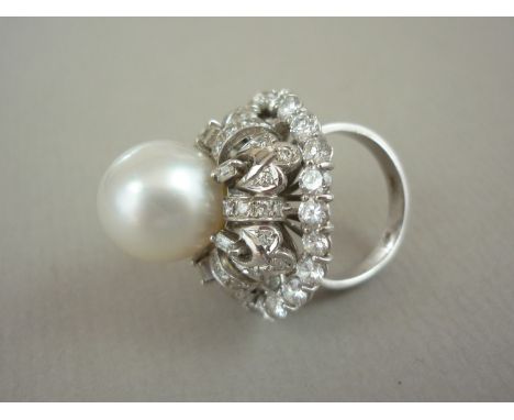 A diamond and pearl cocktail ring, in high carat white metal, with central pearl held above a tiered and open arrangement of 