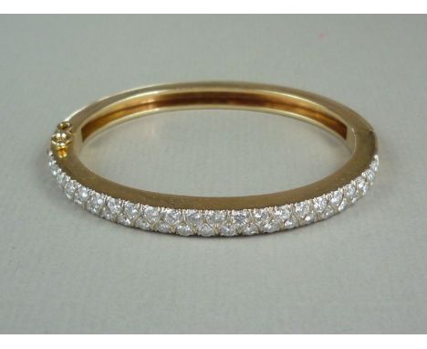 A diamond and yellow metal hinged bangle, the face set with precious white metal, wishbone engraved and pavé set with round-c