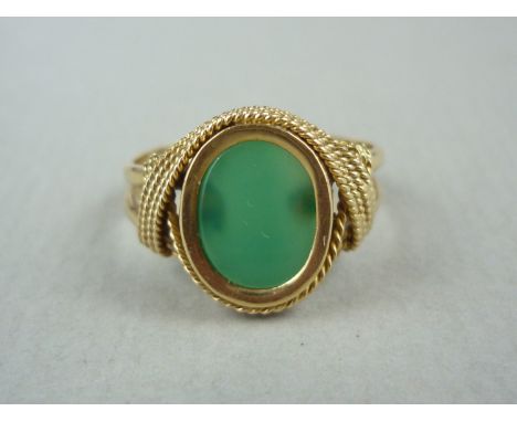 A vintage jade and yellow metal signet ring, with sunken set hardstone matrix held above a yellow metal shank with bifurcated