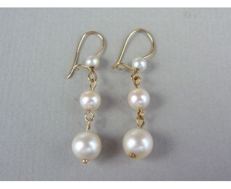 A pair of pearl and yellow metal pendant earrings, each comprising three graded pearls suspended from wires, test as gold