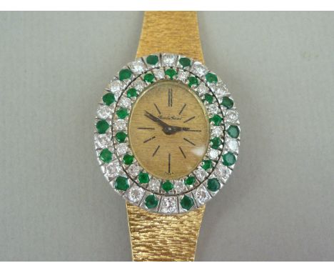 A vintage Bueche Ginod 18ct gold, diamond and emerald cocktail watch, having a mechanical movement, textured oval face and ba