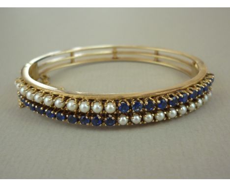 A high-carat yellow metal sapphire and pearl hinged bangle, the face claw-set with adorsed parallel bands of stones, stamped 