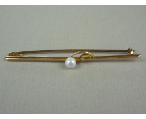 An early 20th Century pearl set yellow metal bar brooch, the gemstone centrally set to the centre of a slender bar, with atta