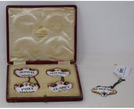 A set of four enamel decanter labels, cased, and another similar 