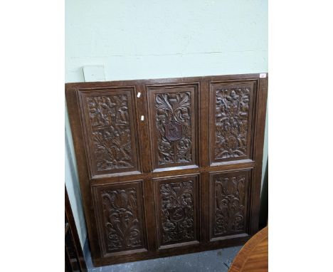 A carved oak panel, each reserve carved with oak leaves and acorns on scrolled leaf and tulip heads, flanking a central panel