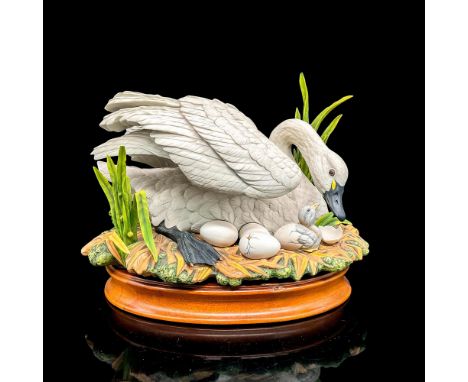 Lovely bisque porcelain figural of a swan with a cygnet and three eggs, 12.25"L x 7.25"W x 8"H. Includes oval wooden stand, 1