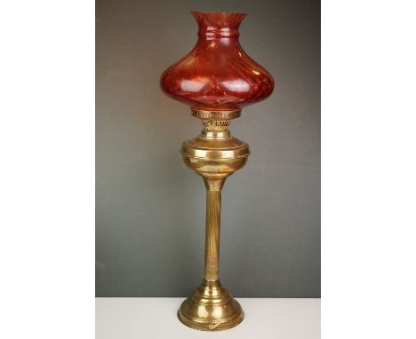A vintage brass oil lamp with orange glass shade converted to electric. 