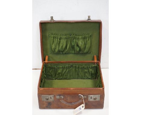 A vintage brown leather suitcase with green lined interior.
