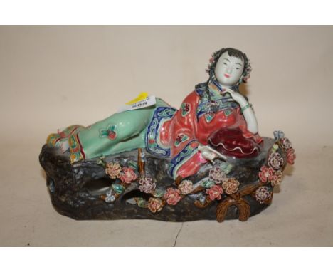 AN ORIENTAL CERAMIC RECLINING LADY HOLDING A BOOK