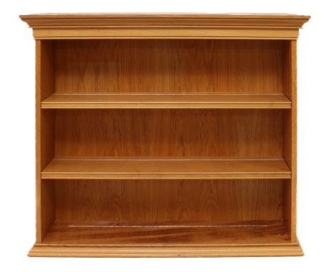 A light-oak open bookcase - believed to be by&nbsp;Thomas Hudson (the 'Cowman') of Odell, Bedfordshire, the ogee moulded top 