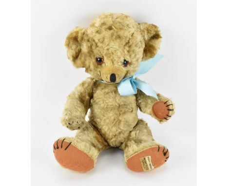 A 1950s/60s Merrythought 'Cheeky' teddy bear, in blonde silky plush, with blue ribbon, glass eyes, jointed, with stitched nos