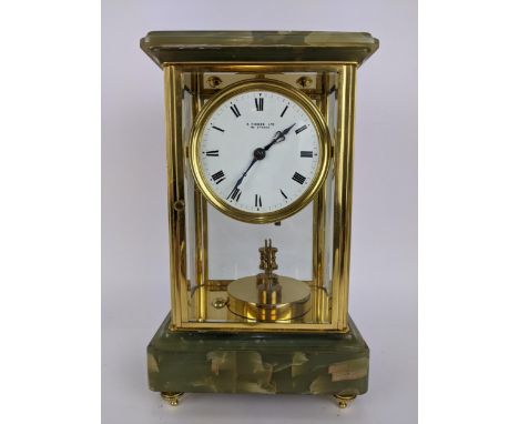 A late 19th century onyx and brass mantle clock, the case having a stepped cornice above a circular white enamel dial inscrib