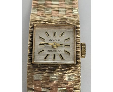 An Avia manual wind ladies 9ct gold wristwatch, having a silvered textured dial with baton numerals, on a 9ct gold integral t