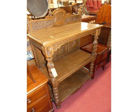A joined  and heavily floral relief carved oak ledgeback three-tier buffet, raised on turned acanthus leaf decorated columns,