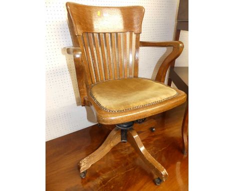 A 1930s oak tub slat back swivel desk elbow chair, raised on roller castors, width 57cmSupports with several areas of damage 