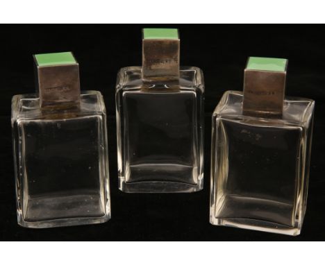 A set of three Asprey & Co Ltd, Art Deco perfume bottles, the silver cube tops with green guilloché enamel panels, London 193