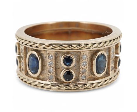 A sapphire and diamond ring, the wide band set to the front with oval and circular-cut sapphires spaced by lines of single-cu