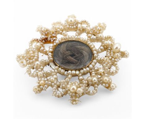 A Georgian seed pearl mourning brooch, early 19th century, designed as a central oval glazed panel of hairwork within a folia