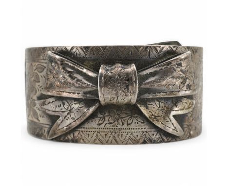 A late Victorian engraved silver wide band bangle, mounted with a tied bow, hallmarked for Birmingham, 1886. Condition - poor