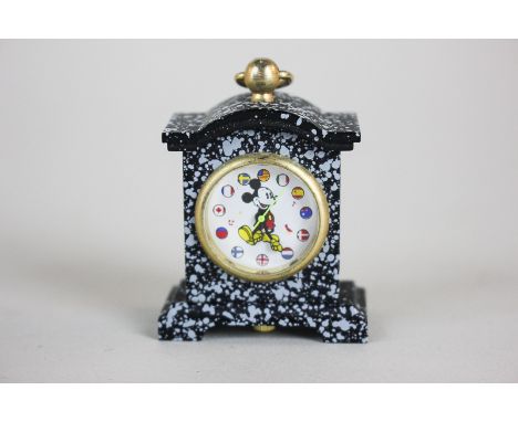 A miniature clock, the face with Mickey Mouse, his hands indicating the time, the numbers replaced with flags of the world, t