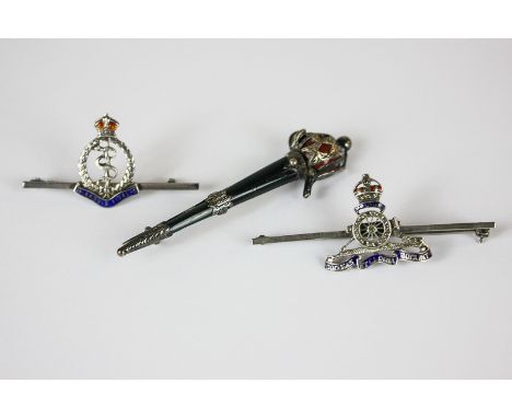 Two silver military cap badges, a Royal Artillery crest and the Royal Army Medical Corps crest, together with a sword brooch 