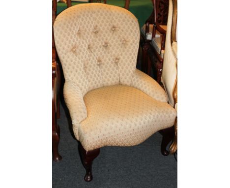 A button back nursing chair upholstered in cream patterned fabric, on cabriole front legs