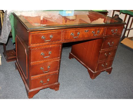 A reproduction mahogany pedestal desk, with red leather inset top and nine drawers, on shaped bracket feet, 122cm