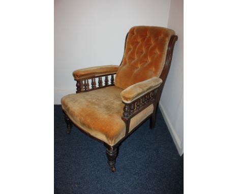 A Victorian upholstered armchair with button upholstered back and padded arms with rail supports, on turned legs and castors